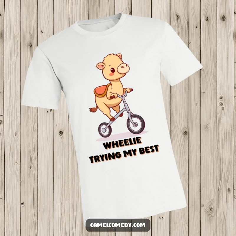 Funny kawaii camel attempting to ride a very small unicycle, looking happy despite wobbling, featured on a fun t-shirt.